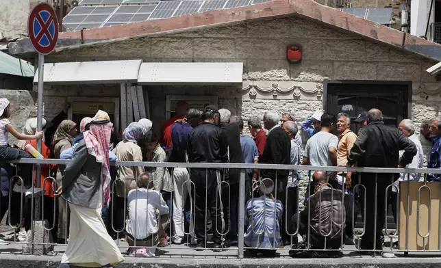 Syrians line up to retrieve money from an ATM in Damascus, Syria, Wednesday, May 14, 2025. (AP Photo/Omar Sanadiki)