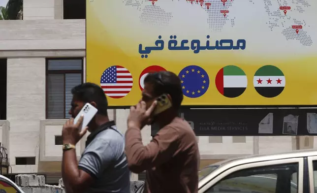 Syrian men speak on their phones on a street in Damascus, Syria, Wednesday, May 14, 2025. (AP Photo/Omar Sanadiki)
