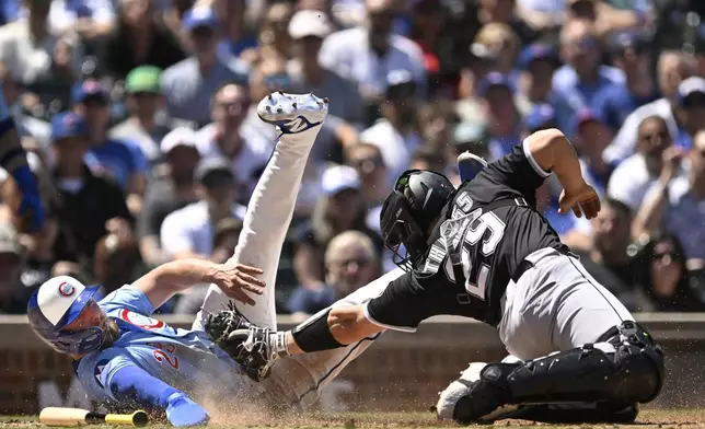 Chicago Cubs' Michael Busch left, slides into home plate safely as Chicago White Sox catcher Matt Thaiss (29) attempts to apply the tag during the second inning of a baseball game Friday, May 16, 2025, in Chicago. (AP Photo/Paul Beaty)