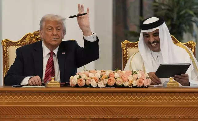 President Donald Trump holds up a pen given by Qatar's Emir Sheikh Tamim bin Hamad Al Thani as they exchange documents during a signing ceremony at the Amiri Diwan in Doha, Qatar, Wednesday, May 14, 2025. (AP Photo/Alex Brandon)