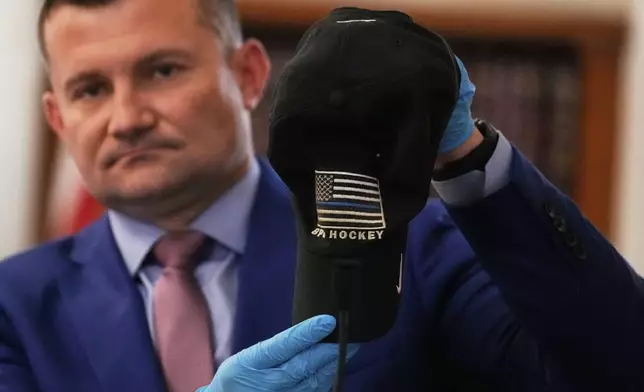 Massachusetts State Police Sergeant Yuriy Bukhenik holds up a hat which was found on the yard where John O'Keefe's body was found during the trial of Karen Read in Norfolk Superior Court, Thursday, May 8, 2025, in Dedham, Mass. (AP Photo/Charles Krupa, Pool)