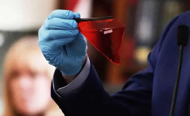 Massachusetts State Police Sergeant Yuriy Bukhenik holds up a red plastic fragment found near where John O'Keefe's body was found during the trial of Karen Read in Norfolk Superior Court, Thursday, May 8, 2025, in Dedham, Mass. (AP Photo/Charles Krupa, Pool)