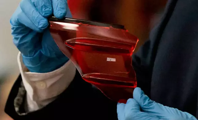 Sgt. Yuriy Bukhenik, of the Massachusetts State Police, displays items of evidence found at the Canton, Mass., scene, while under questioning by special prosecutor Hank Brennan, as he returns to the witness stand in the murder retrial of Karen Read in Norfolk Superior Court, Monday, May 12, 2025, in Dedham, Mass. (Pat Greenhouse/The Boston Globe via AP, Pool)