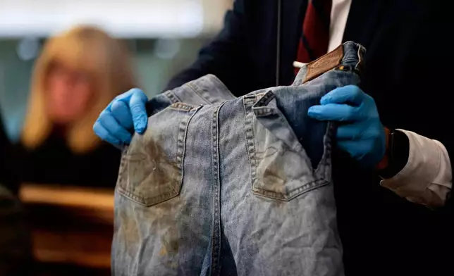Sgt. Yuriy Bukhenik, of the Massachusetts State Police, holds the stained jeans cut from Boston Police officer John O'Keefe as he returns to the witness stand in the murder retrial of Karen Read in Norfolk Superior Court, Monday, May 12, 2025, in Dedham, Mass. (Pat Greenhouse/The Boston Globe via AP, Pool)
