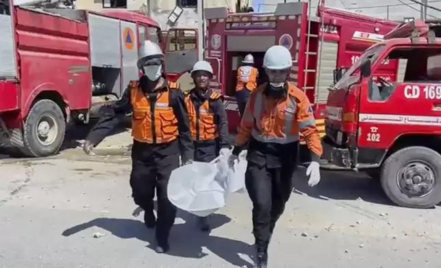 In this frame grab from a video released by Gaza Civil Defense, workers collect human remains after an Israeli strike on a home in Khan Younis killed nine of a doctor's ten children while she was at work, according to Ahmad al-Farra, head of the pediatric department at Nasser Hospital, in Khan Younis, Gaza Strip, Saturday, May 24, 2025. (Gaza Civil Defense via AP)
