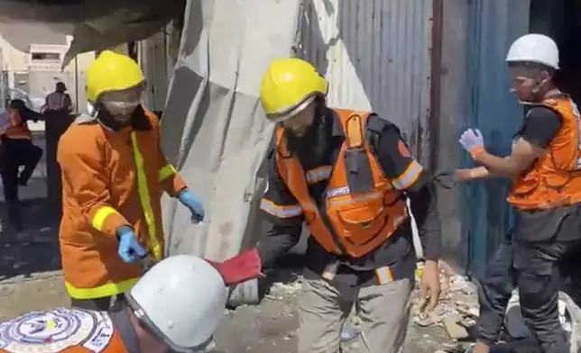In this frame grab from a video released by Gaza Civil Defense, workers collect human remains after an Israeli strike on a home in Khan Younis killed nine of a doctor's ten children while she was at work, according to Ahmad al-Farra, head of the pediatric department at Nasser Hospital, in Khan Younis, Gaza Strip, Saturday, May 24, 2025. (Gaza Civil Defense via AP)
