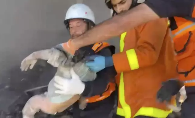 In this frame grab from a video released by Gaza Civil Defense, workers collect the remains a a child after an Israeli strike on a home in Khan Younis killed nine of a doctor's ten children while she was at work, according to Ahmad al-Farra, head of the pediatric department at Nasser Hospital, in Khan Younis, Gaza Strip, Saturday, May 24, 2025. (Gaza Civil Defense via AP)