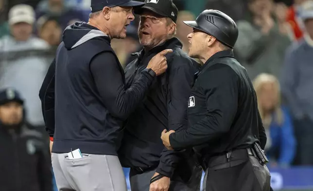 New York Yankees manager Aaron Boone, left, argues with home plate umpires Mark Wegner, right, and first base umpire Bruce Dreckman after getting thrown out of a baseball game against the Seattle Mariners in the ninth inning, Tuesday, May 13, 2025, in Seattle. (AP Photo/Stephen Brashear)