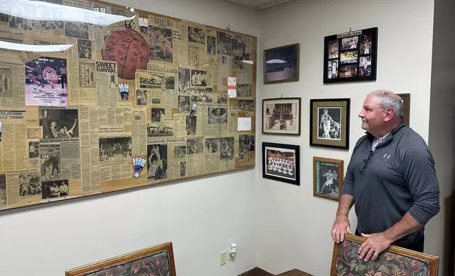 Paintsville, Ky. Mayor Bill Mike Runyon stands in his office and looks at newspapers clippings from his days as a state championship high school basketball coach, Friday, May 16, 2025. (AP Photo/Bill Barrow)