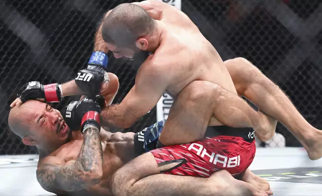 Aiemann Zahabi, top, punches Jose Aldo, bottom, during their UFC 315 featherweight mixed martial arts bout in Montreal, Saturday, May 10, 2025. (Graham Hughes/The Canadian Press via AP)