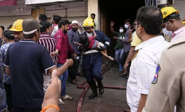 A young child, who was injured when a building caught fire near the Charminar area in Hyderabad, is carried by a rescuer to an ambulance, India, Sunday, May 18, 2025. (AP Photo/Mahesh Kumar A.)