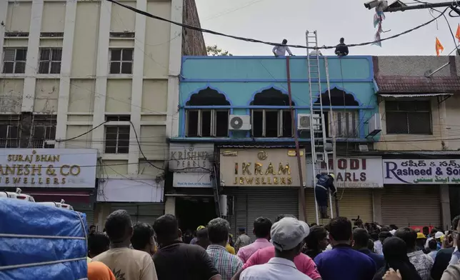 People watch as fire officials conduct rescue operations at a building following a fire in Hyderabad, India, Sunday, May 18, 2025. (AP Photo/Mahesh Kumar A.)