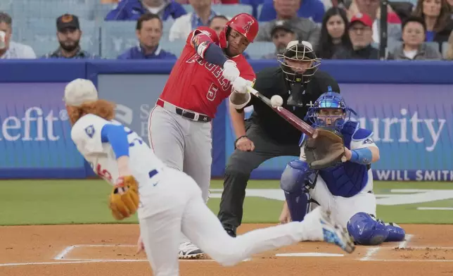 Los Angeles Angels' Yoan Moncada, second from left, hits a two-run home run as Los Angeles Dodgers starting pitcher Dustin May, left, watches along with catcher Will Smith during the first inning of a baseball game Friday, May 16, 2025, in Los Angeles. (AP Photo/Mark J. Terrill)
