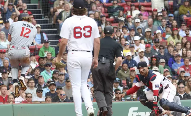 Minnesota Twins's Harrison Bader (12) leaps after hitting home plate ahead of a throw to Boston Red Sox catcher Carlos Narváez, right, during the eighth inning of a baseball game, Sunday, May 4, 2025, in Boston. (AP Photo/Mark Stockwell)