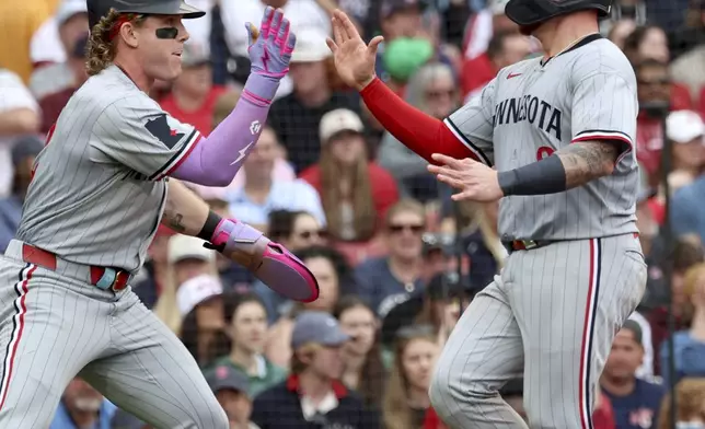 Minnesota Twins' Christian Vázquez, right, high-fives teammate Harrison Bader, left, after scoring a run during the seventh inning of a baseball game against the Boston Red Sox, Sunday, May 4, 2025, in Boston. (AP Photo/Mark Stockwell)