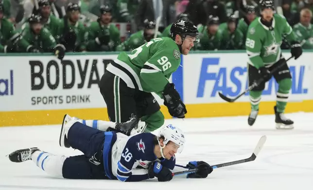 Winnipeg Jets center Morgan Barron (36) falls to the ice competing against Dallas Stars' Mikko Rantanen (96) in the first period of Game 3 of a second-round NHL hockey playoff series in Dallas, Sunday, May 11, 2025. (AP Photo/Julio Cortez)