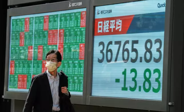 A person walks in front of an electronic stock board showing Japan's Nikkei index at a securities firm Thursday, May 8, 2025, in Tokyo. (AP Photo/Eugene Hoshiko)