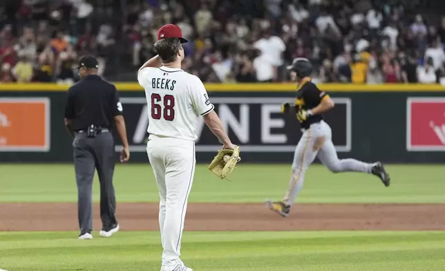Arizona Diamondbacks pitcher Jalen Beeks (68) pauses in the infield after giving up a three-run home run to Pittsburgh Pirates' Bryan Reynolds, right, during the eighth inning of a baseball game Tuesday, May 27, 2025, in Phoenix. (AP Photo/Ross D. Franklin)
