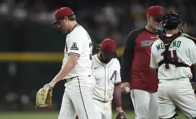 Arizona Diamondbacks pitcher Kevin Ginkel, left, walks off the field after being taking out by Diamondbacks manager Torey Lovullo, second from right, as catcher Gabriel Moreno, right, and third baseman Eugenio Suárez pause near the pitcher's mound during the eighth inning of a baseball game against the Pittsburgh Pirates Tuesday, May 27, 2025, in Phoenix. (AP Photo/Ross D. Franklin)
