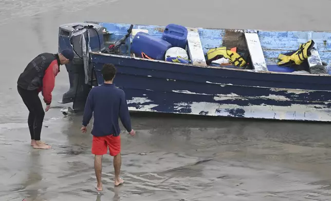 Del Mar lifeguards looks over a capsized boat on the beach Monday, May 5, 2025, in at Torrey Pines State beach in San Diego, Calif. (AP Photo/Denis Poroy)
