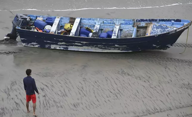 A Del Mar lifeguard looks over a capsized boat on the beach Monday, May. 5, 2025, in at Torrey Pines State beach in San Diego, Calif. (AP Photo/Denis Poroy)