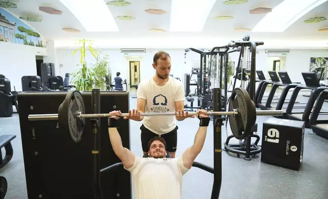 Personal trainer Valerio Masella, 26, who trained Robert Francis Prevost before the cardinal became Pope Leo XIV, helps his colleague Giorgio Vaccarella in his gym near the Vatican, Wednesday, May 21, 2025. (AP Photo/Alessandra Tarantino)