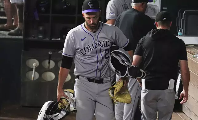 Colorado Rockies catcher Jacob Stallings (25) carries his gear as he walks from the dugout at the end of a baseball game against the Texas Rangers, Wednesday, May 14, 2025, in Arlington, Texas. (AP Photo/LM Otero)