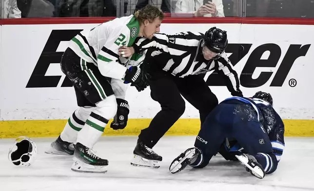 Linesman Devin Berg (87) gets between Dallas Stars' Roope Hintz (24) and Winnipeg Jets' Dylan Demelo (2) during the third period of an NHL hockey playoff series in Winnipeg, Manitoba, Wednesday, May 7, 2025. (Fred Greenslade/The Canadian Press via AP)