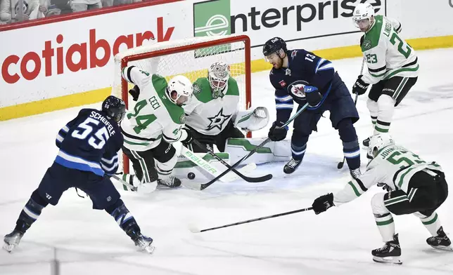 Dallas Stars goaltender Jake Oettinger (29) makes the save on Winnipeg Jets' Mark Scheifele (55) as Gabriel Vilardi (13) looks for the rebound during the third period of an NHL playoff hockey game in Winnipeg, Canada, Wednesday, May 7, 2025. (Fred Greenslade/The Canadian Press via AP)