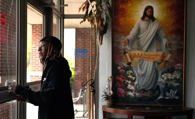 Tazz Webster, who ultimately wound up homeless after an apartment manager allegedly ridiculed and shoved him because he is transgender, exits through the front door of a community center, April 9, 2025, in St. Louis. (AP Photo/Jeff Roberson)