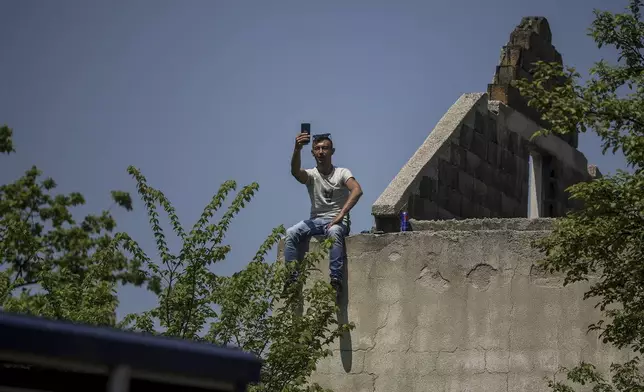 A man watches the bullfights from an abandoned house in Bijelo Polje, Bosnia, Sunday, May 11, 2025. (AP Photo/Armin Durgut)