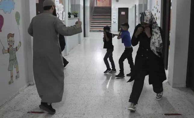 Students and teachers react to tear gas fired by Israeli Police into in the yard of the UNRWA Boys' School run by the U.N. agency for Palestinian refugees in the Shuafat Refugee Camp in east Jerusalem, Tuesday, April 29, 2025.(AP Photo/Mahmoud Illean)