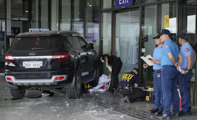 First responders work the scene after a vehicle drove into a departures entrance at Manila's International Airport terminal 1, in Manila, Philippines, Sunday, May 4, 2025. (AP Photo/Aaron Favila)