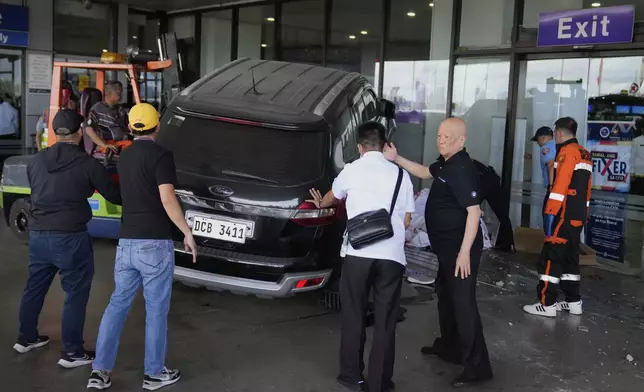 San Miguel Corp. president and CEO and Ninoy Aquino International Airport (NAIA) Infra Corp. chairman Ramon Ang, second from right, helps first responders after a vehicle drove near the departure entrance at Manila's International Airport Terminal 1, killing some people while injuring others in Manila, Philippines on Sunday, May 4, 2025. (AP Photo/Aaron Favila)s