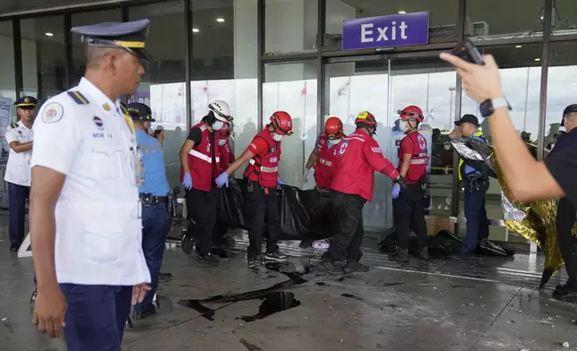 Rescuers carry a body of a victim after a vehicle drove into a departures entrance at Manila's International Airport terminal 1, in Manila, Philippines, Sunday, May 4, 2025. (AP Photo/Aaron Favila)