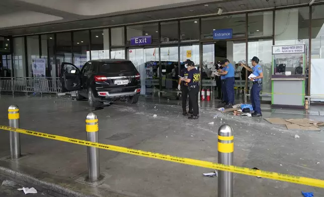 First responders work the scene after a vehicle drove into a departures entrance at Manila's International Airport, in Manila, Philippines, Sunday, May 4, 2025. (AP Photo/Aaron Favila)