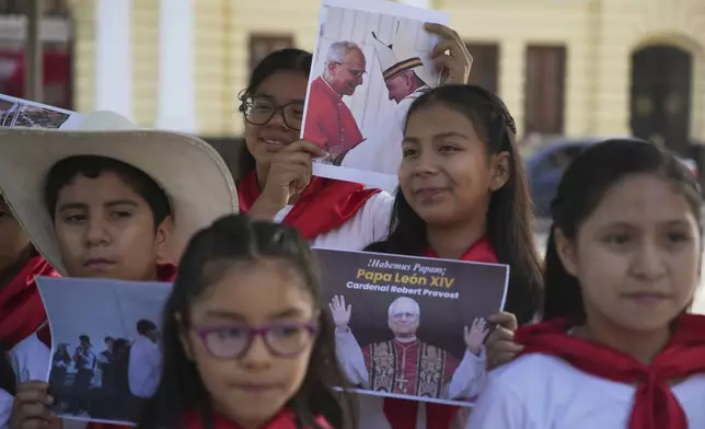 A religious children's choir displays photos of newly elected Pope Leo XIV after performing to celebrate his election as pope outside the Santa Maria Cathedral, the episcopal see of the Diocese of Chiclayo, Peru, where he served as bishop, Friday, May 9, 2025. (AP Photo/Guadalupe Pardo)