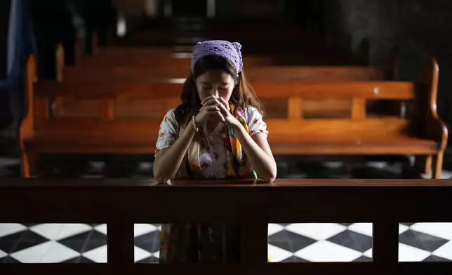 Catholic Mechaela Rejano prays at the Imus Cathedral at Imus, Cavite province, Philippines on Friday, May 9, 2025. (AP Photo/Aaron Favila)