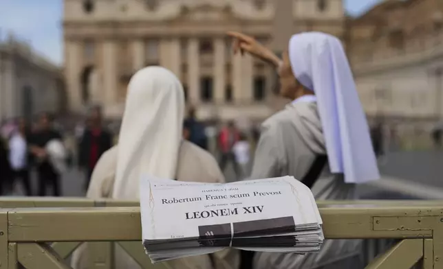 Nuns stand next to copies of L'Osservatore Romano newspaper with headlines in Latin of Pope Leo XIV at the Vatican, Friday, May 9, 2025, a day after he was elected as the first North American pope. (AP Photo/Francisco Seco)