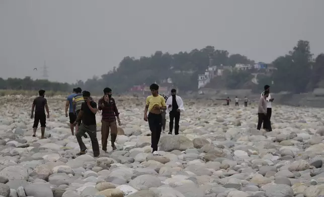 People cross the Chenab River after the flow of water was halted from a dam, at Akhnoor, on the outskirts of Jammu, India, Monday, May 5, 2025. (AP Photo/Channi Anand)