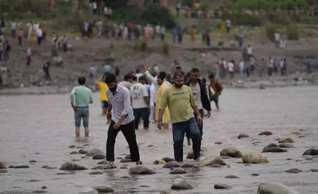 People cross the Chenab River after the flow of water was halted from a dam, at Akhnoor, on the outskirts of Jammu, India, Monday, May 5, 2025. (AP Photo/Channi Anand)