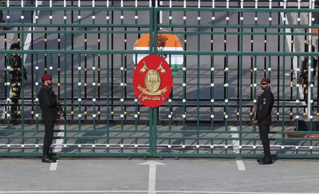 Pakistan's Rangers soldiers, in black, and Indian Border Security Forces soldiers, behind the gate, stand guard during a daily closing ceremony at the Wagah, a joint post on the Pakistan and India border, near Lahore, Pakistan, Monday, May 5, 2025. (AP Photo/K.M. Chaudary)