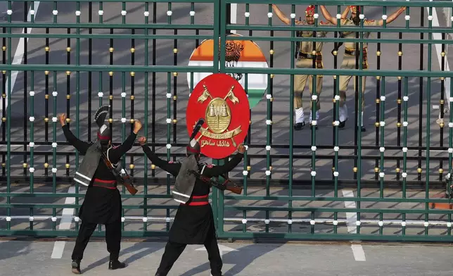 Pakistan's Rangers soldiers, in black, and Indian Border Security Forces soldiers, behind gate, gesture each others during a daily closing ceremony at the Wagah, a joint post on the Pakistan and India border, near Lahore, Pakistan, Monday, May 5, 2025. (AP Photo/K.M. Chaudary)