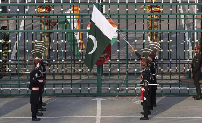 Pakistan's Rangers soldiers, in black, and Indian Border Security Forces soldiers, behind the gate, lower their flags during a daily closing ceremony at the Wagah, a joint post on the Pakistan and India border, near Lahore, Pakistan, Monday, May 5, 2025. (AP Photo/K.M. Chaudary)