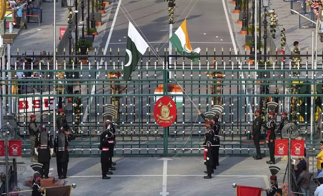Pakistan's Rangers soldiers, in black, and Indian Border Security Forces soldiers, behind the gate, lower their flags during a daily closing ceremony at the Wagah, a joint post on the Pakistan and India border, near Lahore, Pakistan, Monday, May 5, 2025. (AP Photo/K.M. Chaudary)