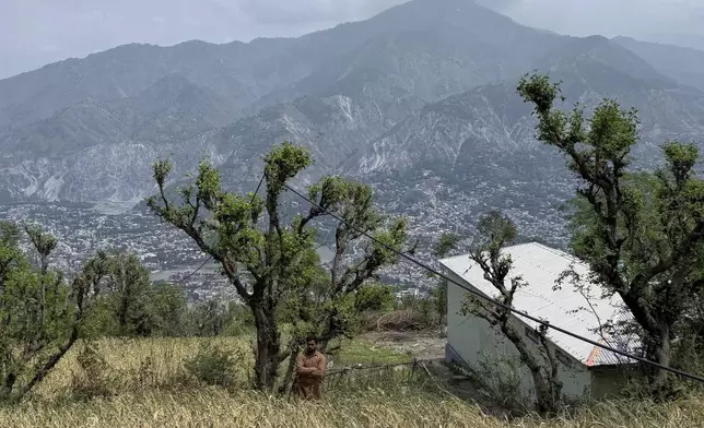 A villager walks through a wheat field during a government's organized trip for media to Bella Noor Shah, a mountainous village near Muzaffarabad, the capital of Pakistan administered Kashmir, Monday, May 5, 2025. (AP Photo/Muhammad Yousuf, Pool)