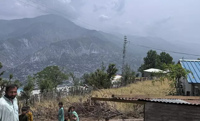Villager walk on a dusty track during a government's organized trip for media to Bella Noor Shah, a mountainous village near Muzaffarabad, the capital of Pakistan administered Kashmir, Monday, May 5, 2025. (AP Photo/Muhammad Yousuf, Pool)