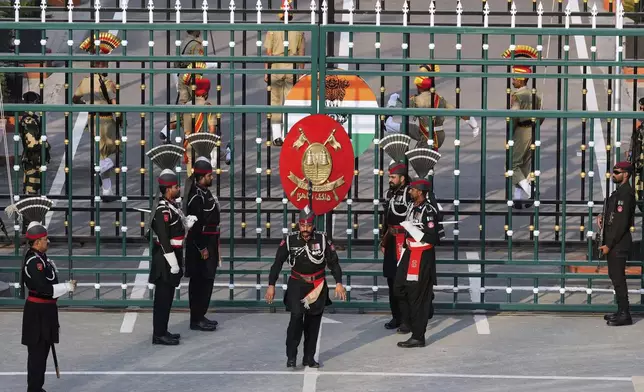 Pakistan's Rangers soldiers, in black, and Indian Border Security Forces soldiers, behind the gate, parade during a daily closing ceremony at the Wagah, a joint post on the Pakistan and India border, near Lahore, Pakistan, Monday, May 5, 2025. (AP Photo/K.M. Chaudary)