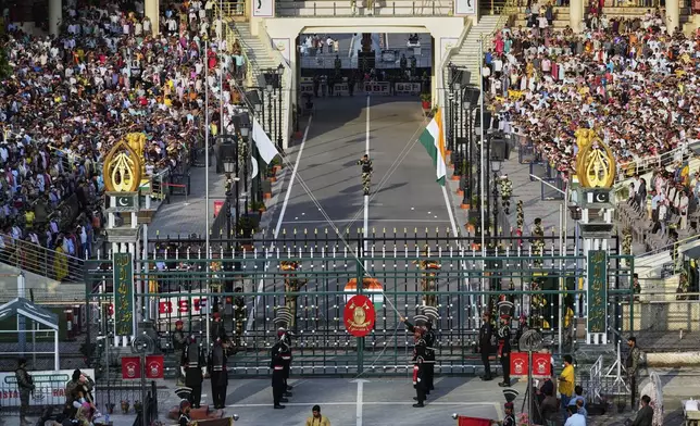 Pakistan's Rangers soldiers, in black, and Indian Border Security Forces soldiers, behind the gate, lower their flags during a daily closing ceremony at the Wagah, a joint post on the Pakistan and India border, near Lahore, Pakistan, Monday, May 5, 2025. (AP Photo/K.M. Chaudary)