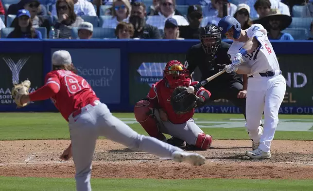 Los Angeles Dodgers' Will Smith, right, hits a three-run home run as Los Angeles Angels relief pitcher Shaun Anderson, left, watches along with catcher Travis d'Arnaud during the seventh inning of a baseball game Sunday, May 18, 2025, in Los Angeles. (AP Photo/Mark J. Terrill)